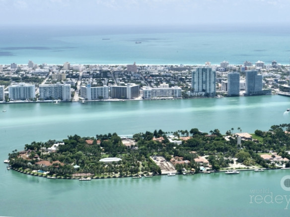 Aerial view of South Florida luxury housing towers and coastal high-rises under bright afternoon sunlight.