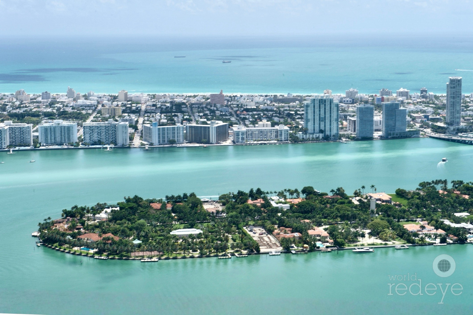 Aerial view of South Florida luxury housing towers and coastal high-rises under bright afternoon sunlight.