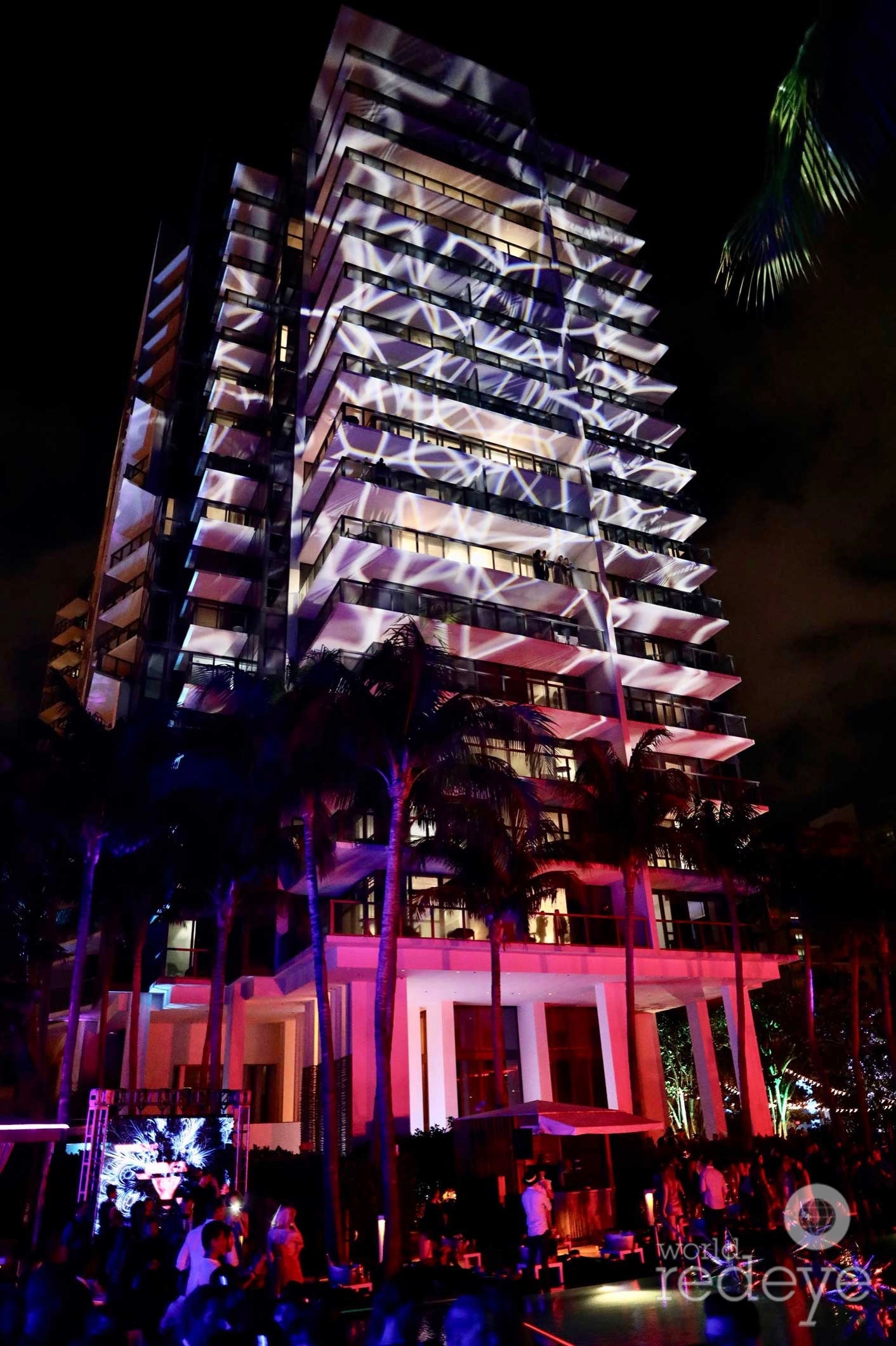 Street view of modern luxury resort buildings and palm trees along Collins Avenue in South Beach Miami.